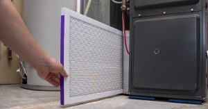 A person installing a furnace filter into an HVAC unit