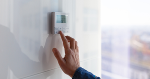 Person setting temperature on a digital thermostat